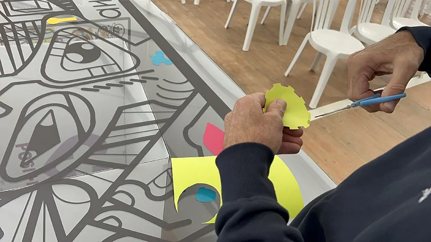 Un symbole d'engrenage découpé dans du vinyle vert clair et collé sur la fresque du tri My Art Box pendant l'animation inaugurale à Albi