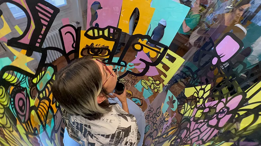 ana artiste est dans son tube plexi transparent en team-building pour avocats à Paris pendant que les participants et invités crée autour la couleurs à l'aide d'un kit de vinyle adhésif
