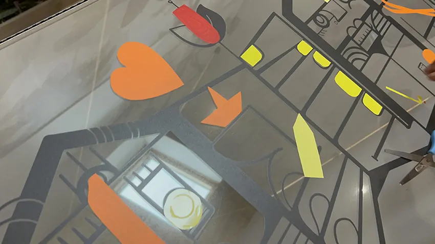 Un cœur orange adhésif découpé et collé par un participant sur la fresque plexi du team building pour architectes à Paris