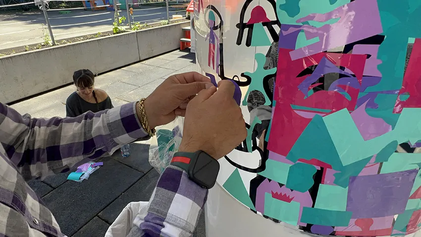 Une participante en train de coller son idées du le plexi cylindrique de aNa artiste lors du team building secteur de la petite enfance à Genève animé par Christophe Chazot