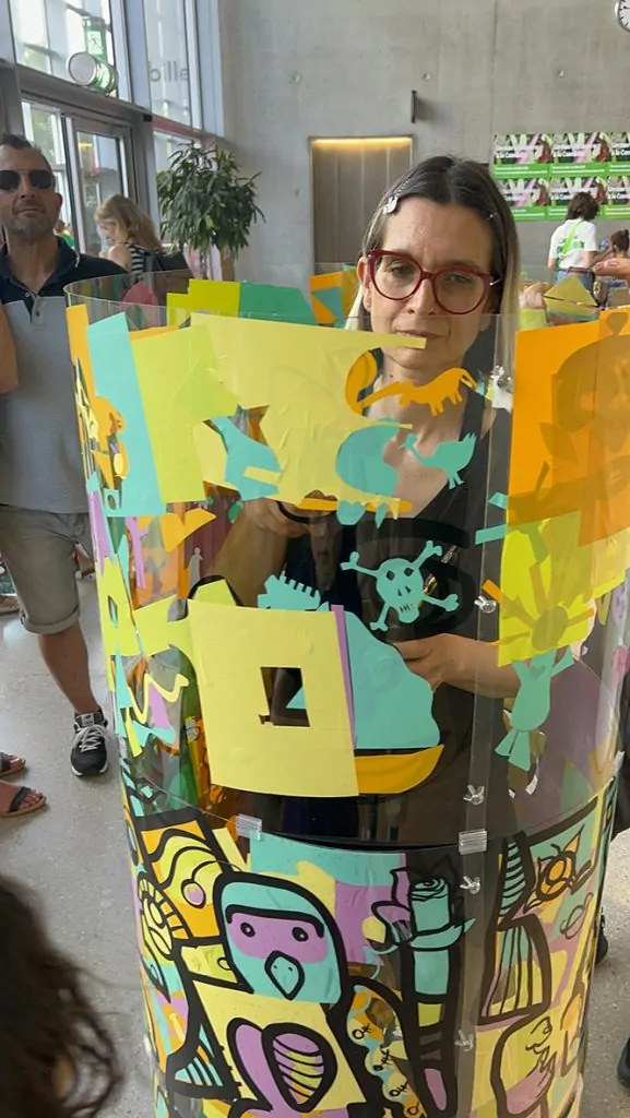 ana artiste en train de peindre dans son cylindre plexiglas et des participants autour lors de l'animation fresque éco-responsable à Genève organisée par My Art Box