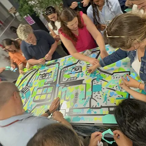 Participants manipulant des chutes de matériaux recyclés pour une fresque collaborative lors d'un séminaire.