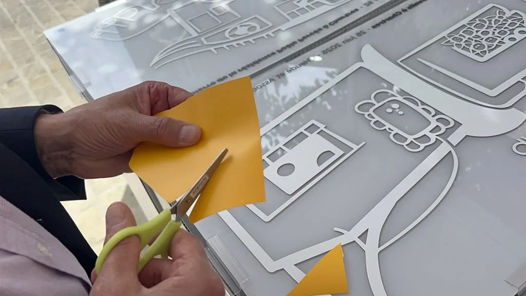 Un découpage d'un sticker orange par un participant aux fresques éco-responsables pose de première pierre à Chartres organisé par My Art Box