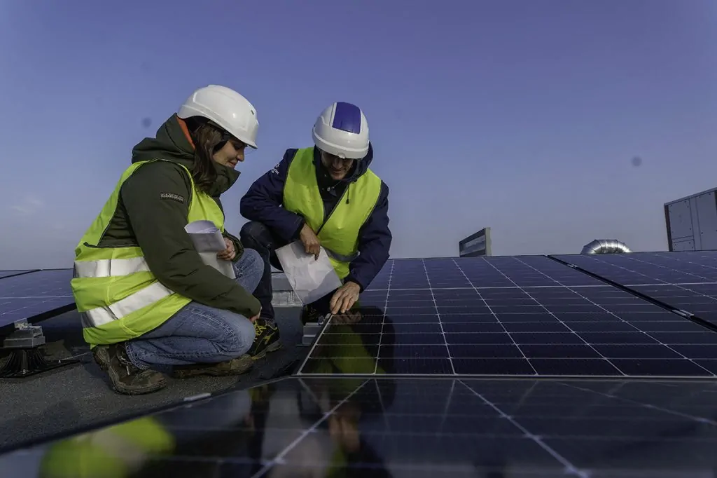 Deux agents sur un toit habillé de panneaux photovoltaïque illustre le jeu des valeurs d'action et de performance Terre et Lac