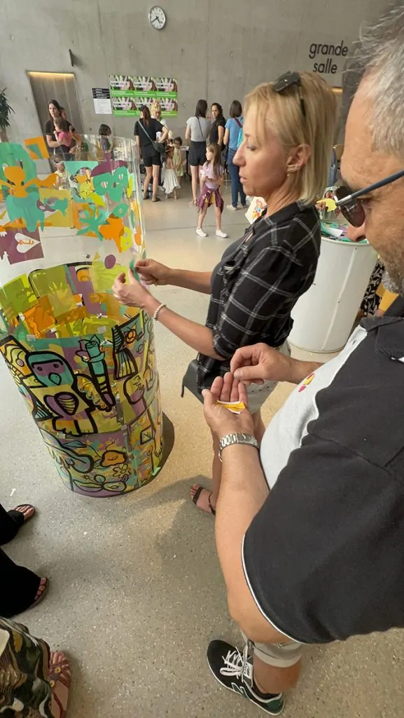Des participants autour du tube en plexiglas de l'artiste aNa en animation fresque éco-responsable à Genève
