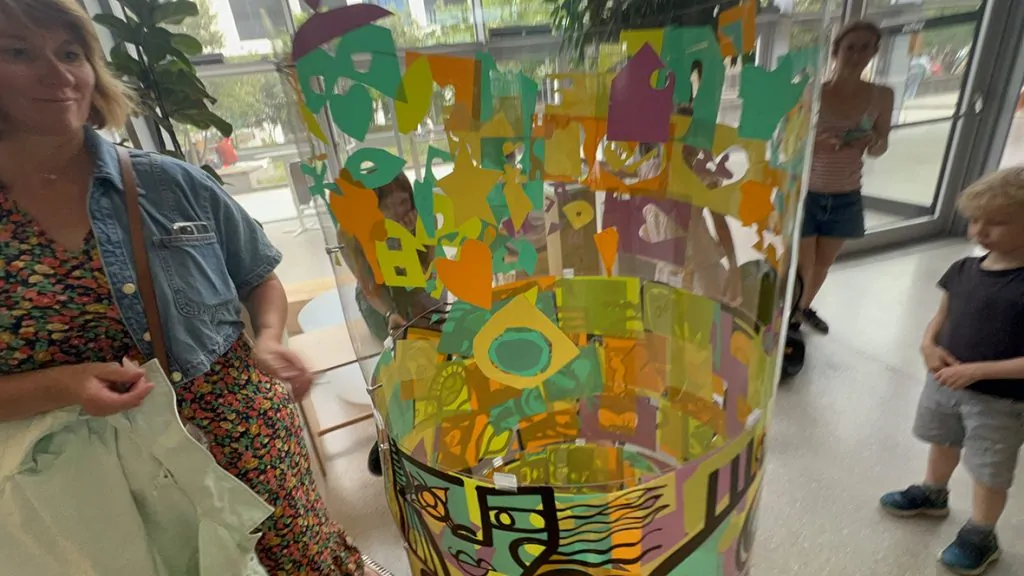 Des participants autour du cylindre en plexiglas de l'artiste aNa pendant l'animation fresque éco-responsable à Genève organisée par My Art Box